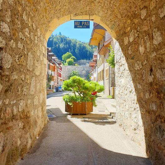 Chemin sous une voute en pierre menant au bourg de Valangin, ciel bleu et soleil